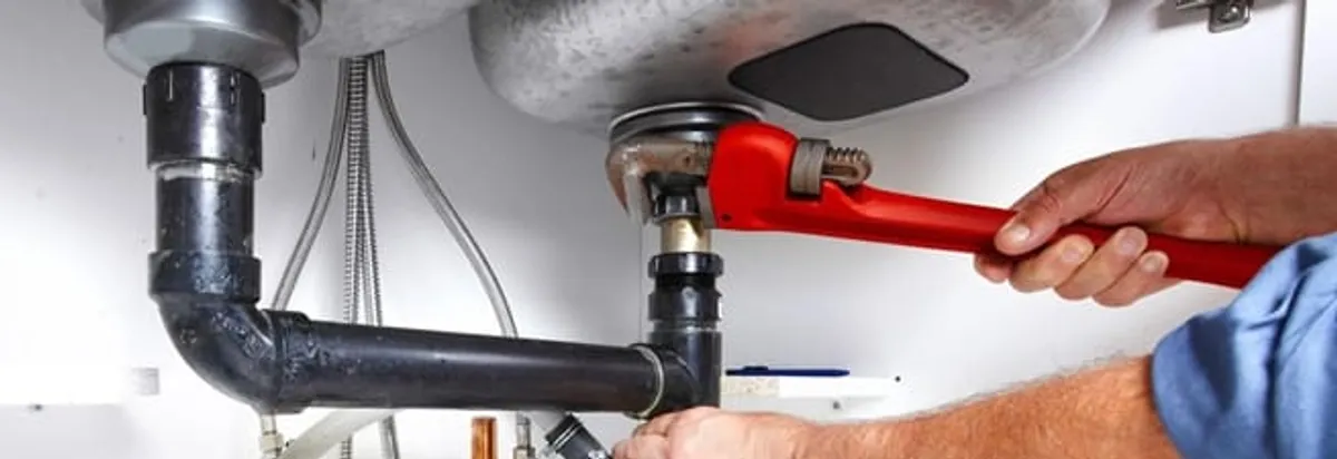 Garbage disposal repair technician tightening the sink drain and disposal connection in Staten Island, NY