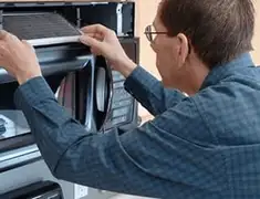 Appliance repair technician replacing a microwave vent filter in Staten Island, NY