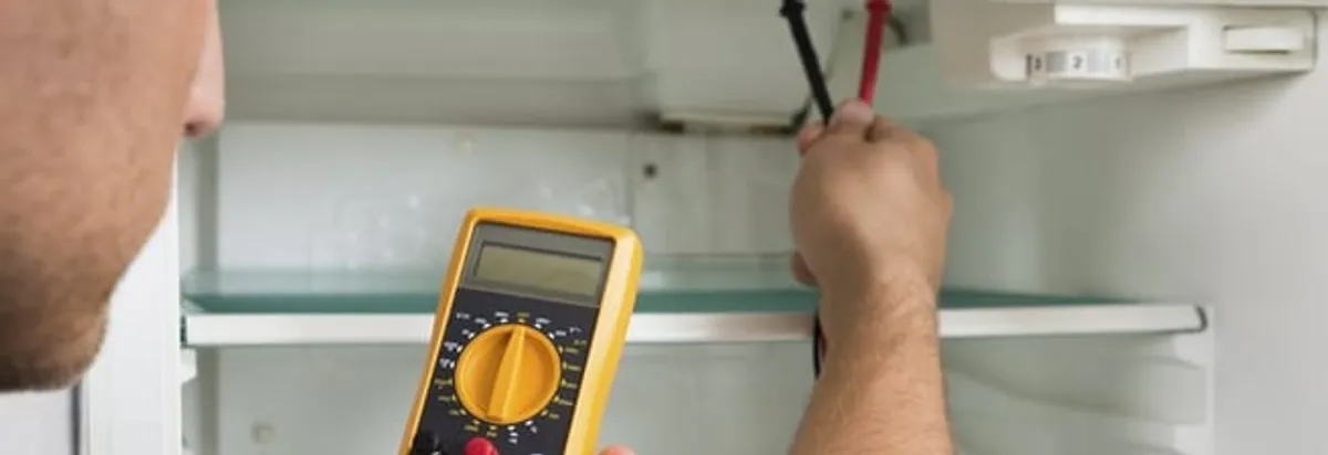 Refrigerator repair technician testing electrical components with a multimeter in Staten Island, NY
